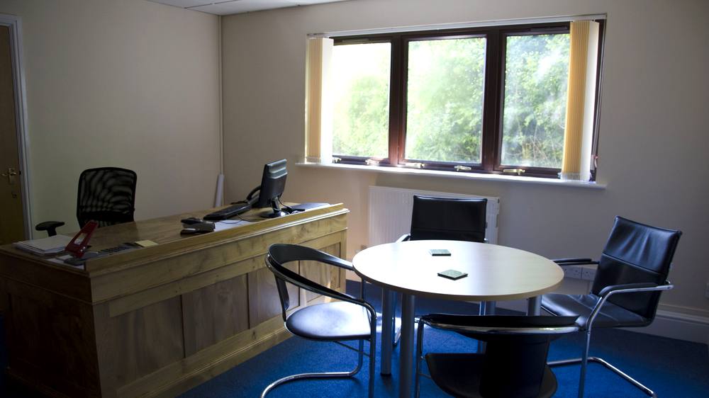 A suite with a desk and a round meeting table by the window